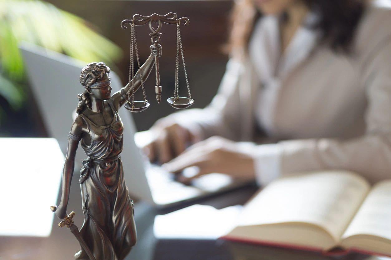 A statue of justice and a person sitting at a desk.