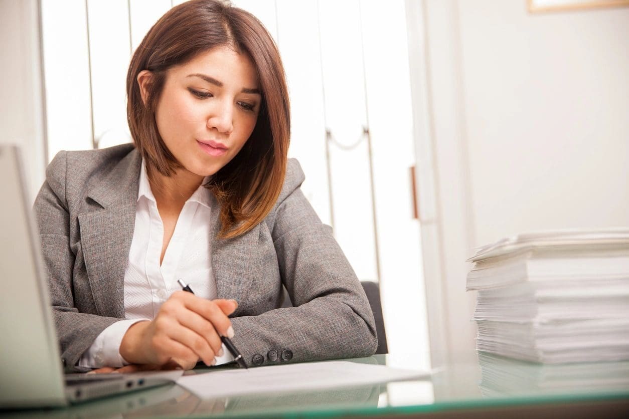 A woman sitting at a desk writing on paper.