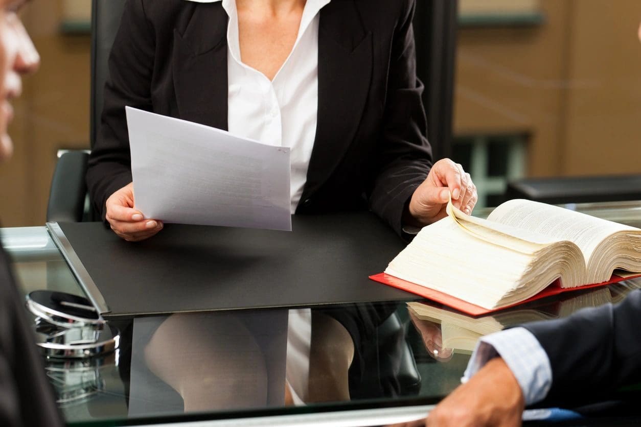 A woman is holding papers and sitting at a table.