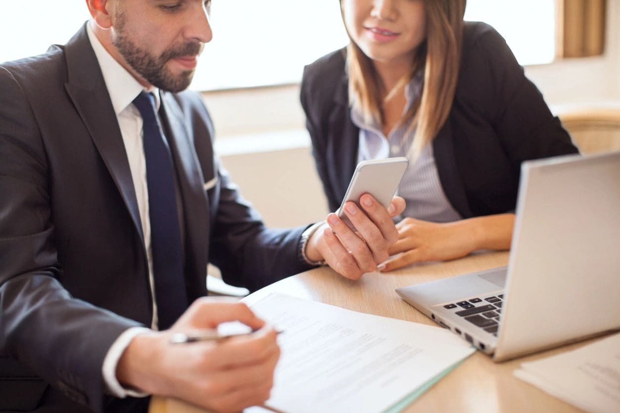 A man and woman sitting at a table with papers.