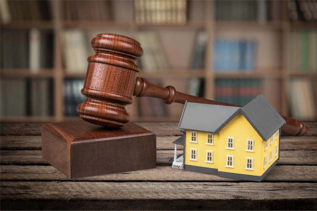 A wooden gavel next to a toy house.