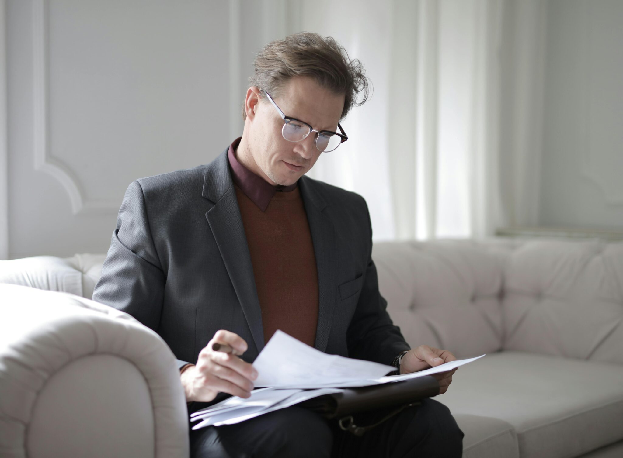 A man sitting on top of a couch writing.