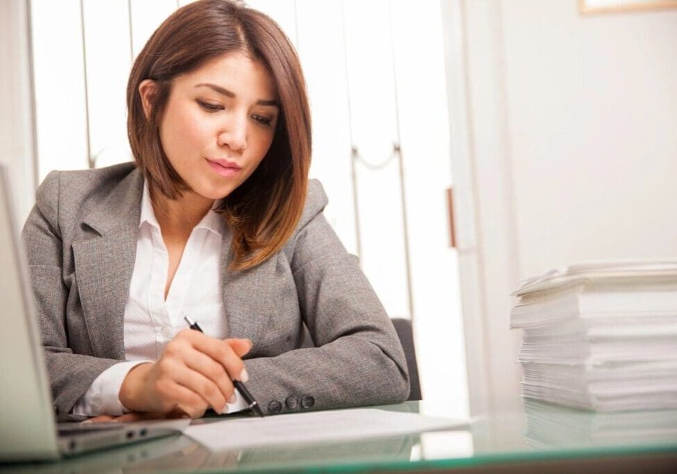 A woman sitting at a desk writing on paper.