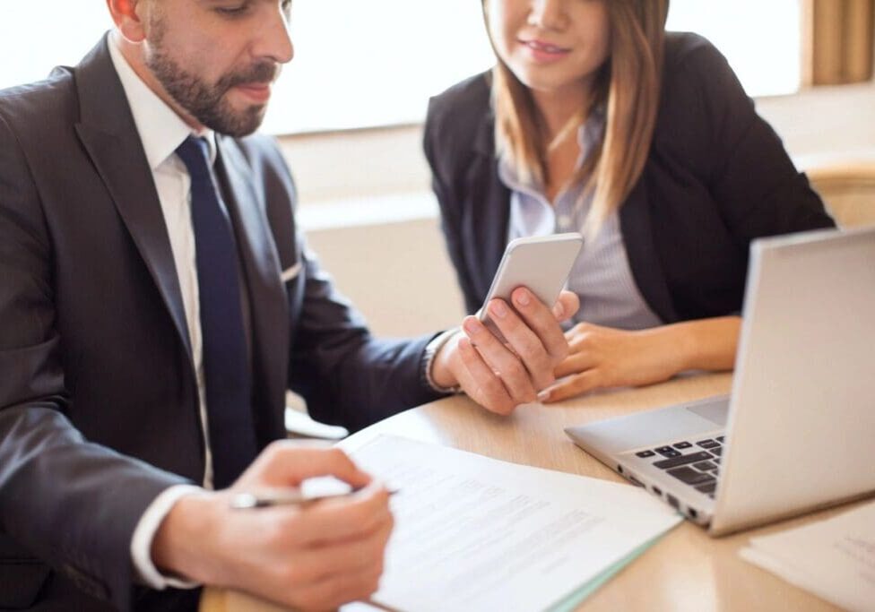 A man and woman sitting at a table with papers.