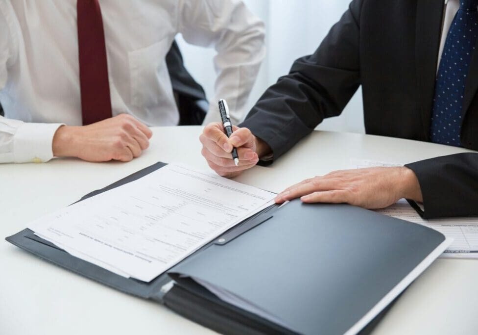 A couple of people sitting at a table with papers.